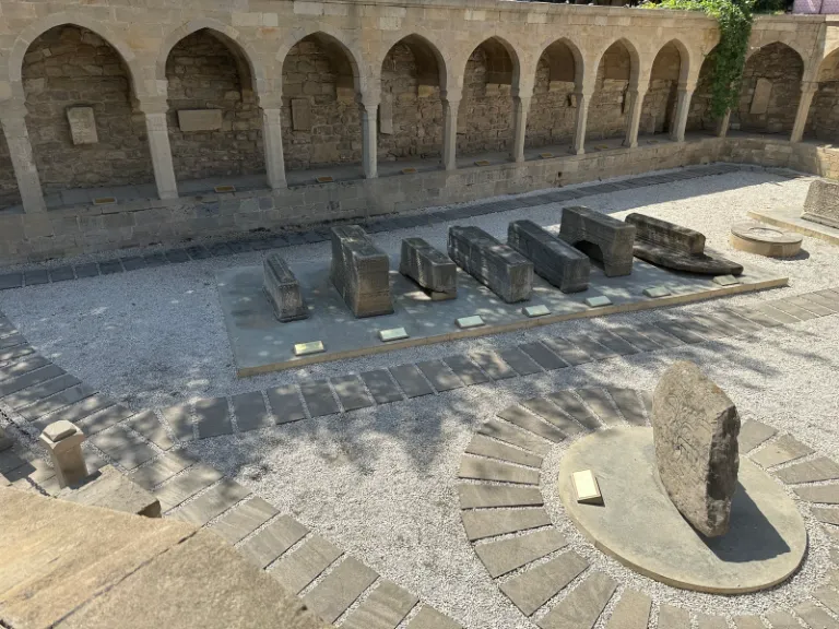 שורת מצבות אבן מסותתות בצורת ארגז לאורך החצר של כיכר הבזאר בבאקו, מול הקשתות (צילום מ-2025)