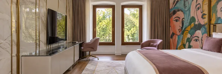 איור AI בהשראת חדר במלון Art Gallery Hotel: חלונות מקושתים, כורסאות בגוון סגלגל, מיטה וציור קיר צבעוני