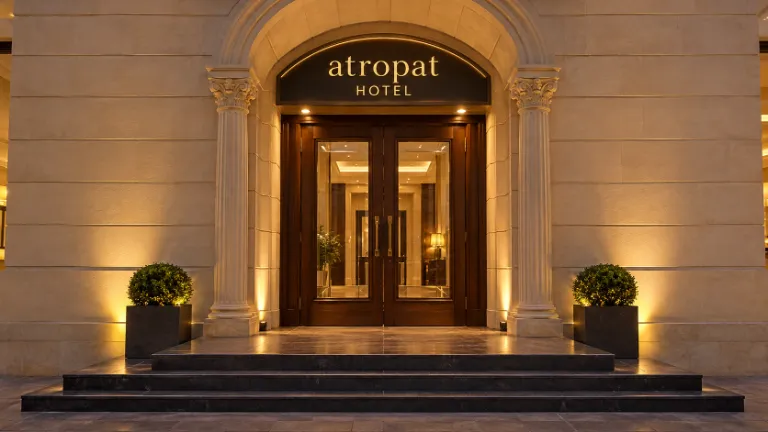איור AI בהשראת תמונת הכניסה של Atropat Old City Hotel: שלט המלון, דלתות עץ וזכוכית, עמודים מחורצים, אבן בהירה, מדרגות ועציצים
